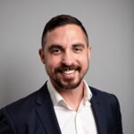 Professional headshot of Steven Whiskeyman, veteran B2B marketing executive and digital analytics strategist, smiling in a navy blazer and white open-collar shirt.